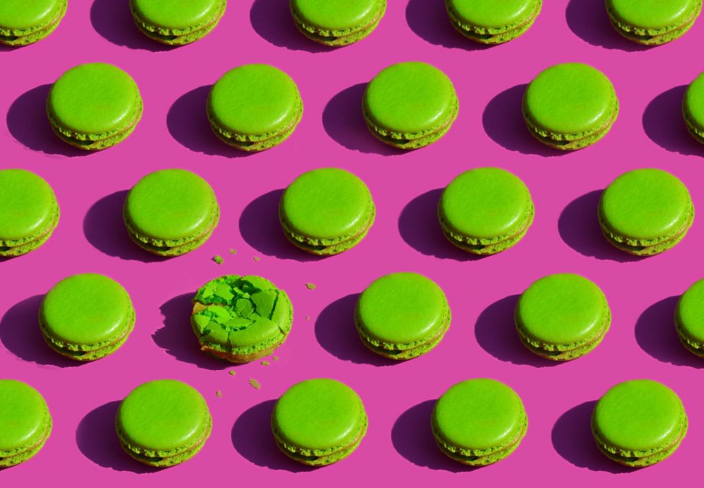 Galletas macaron verdes sobre fondo rosa.